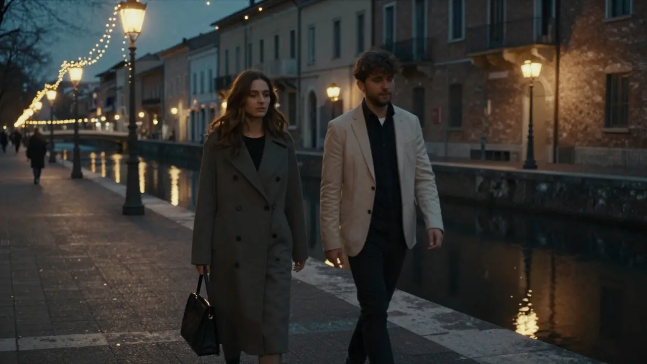 Two people walking peacefully along the Navigli canal in Milan under string lights.
